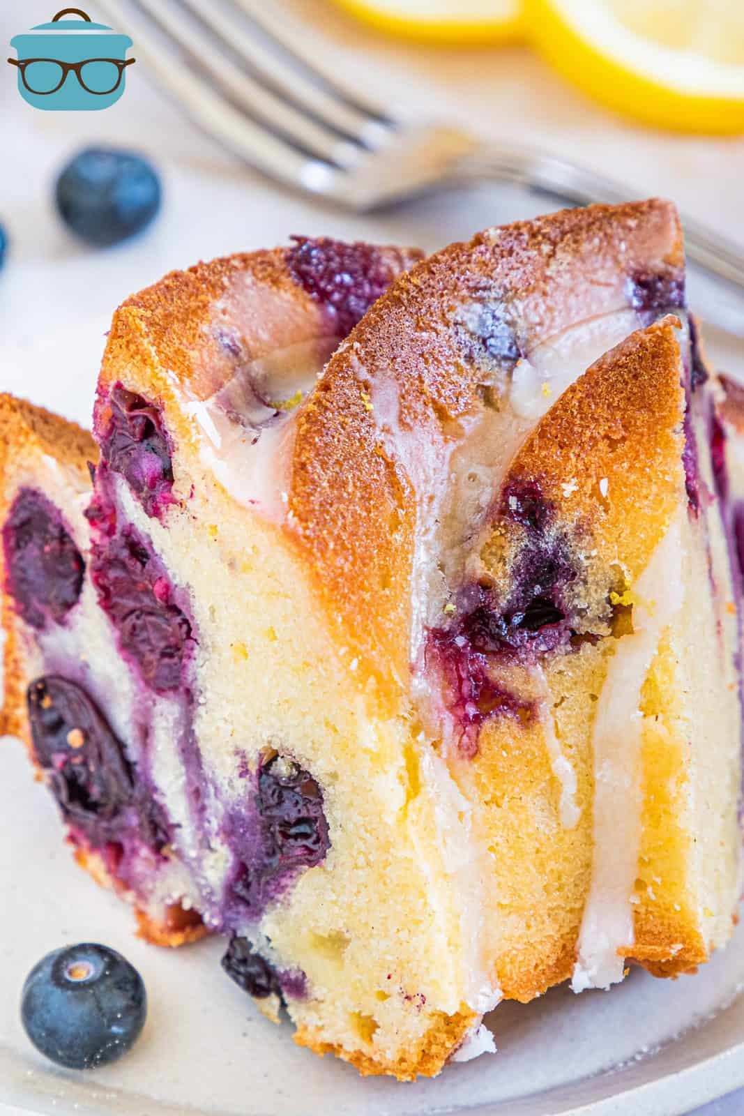 Overhead, close up photoof one slice of Lemon Blueberry Pound Cake with fork in background.