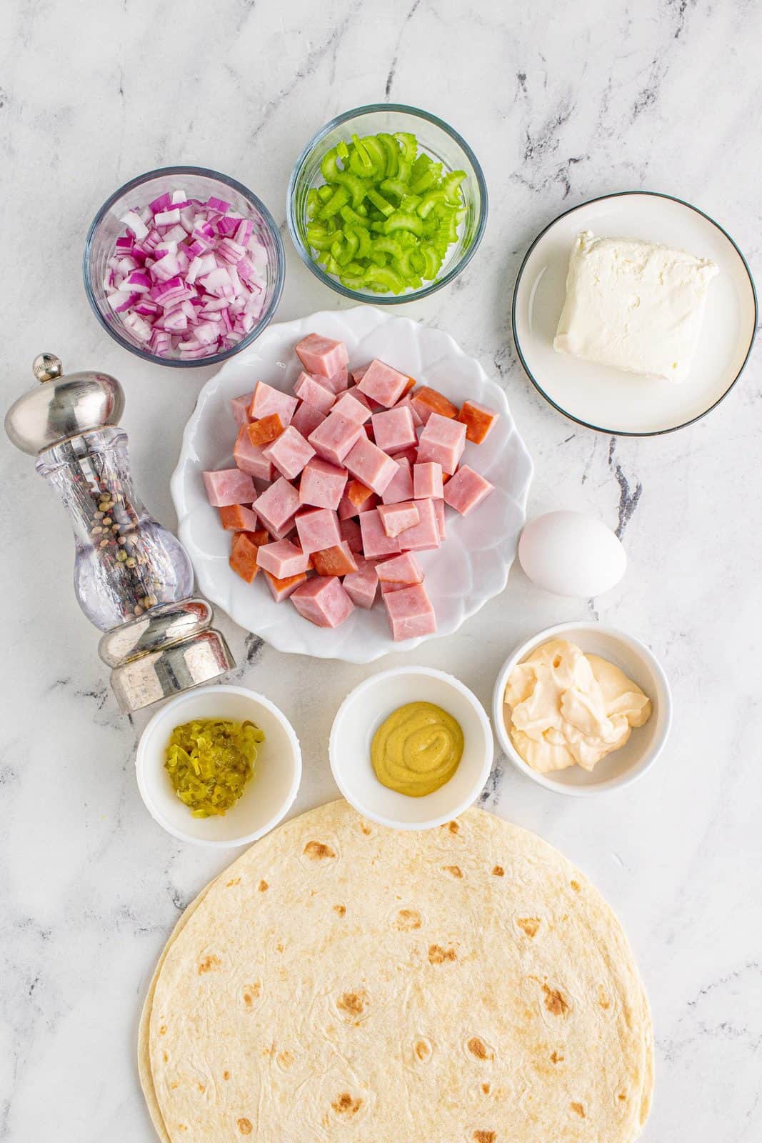 Ingredients needed: cooked ham, hard-boiled egg, celery, red onion, cream cheese, mayonnaise, dijon mustard, sweet pickle relish, black pepper and tortillas.