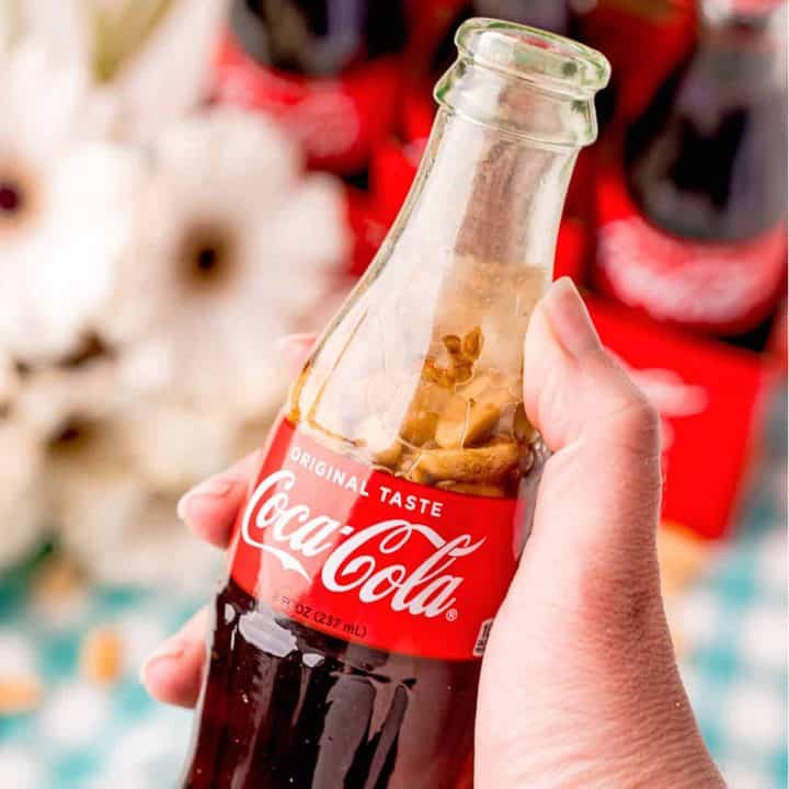 Square image of hand holding Coca-Cola and Peanuts