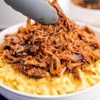 Square image of pulled pork being added to macaroni and cheese