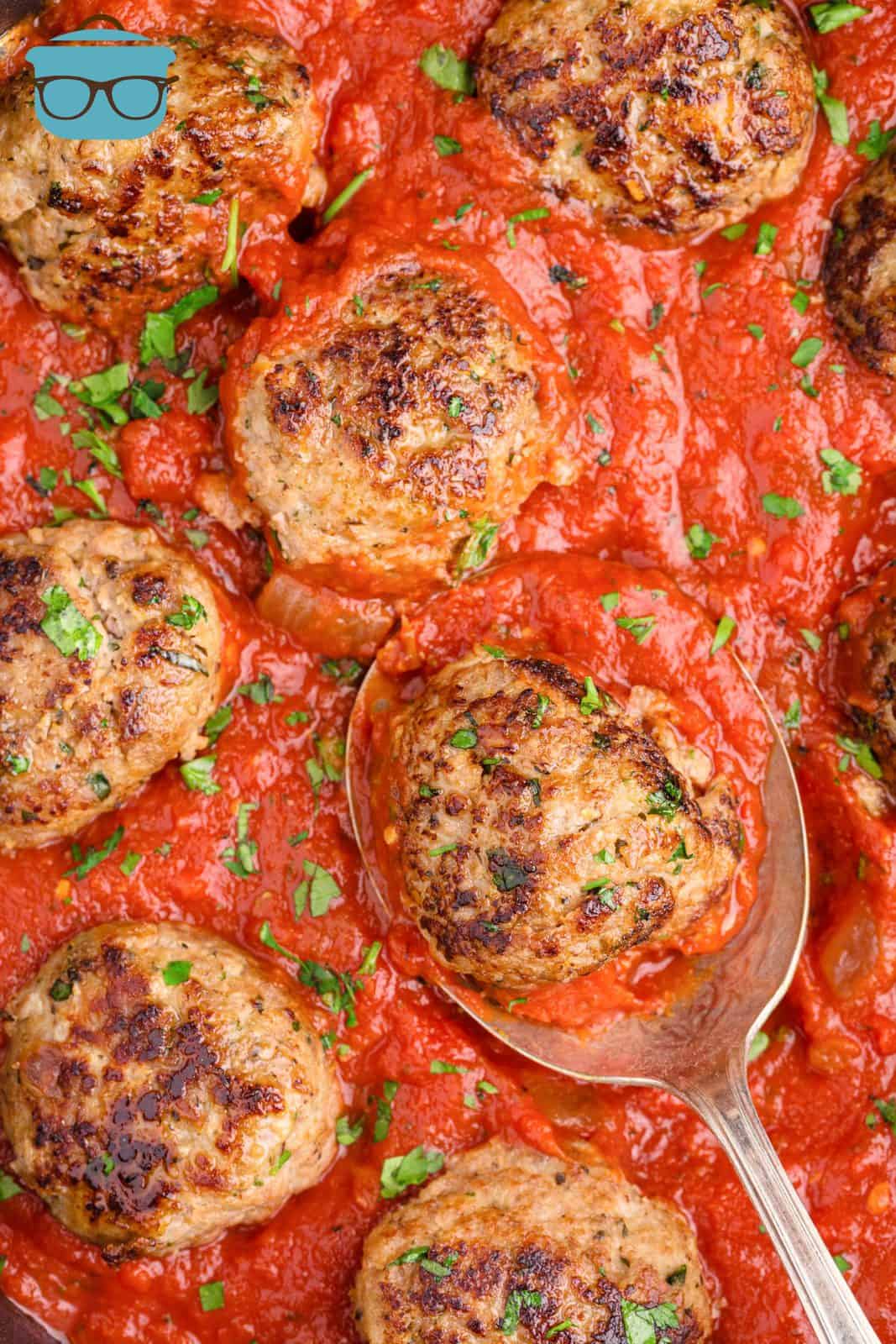 Homemade Turkey Meatballs in sauce with parsley and spoon.