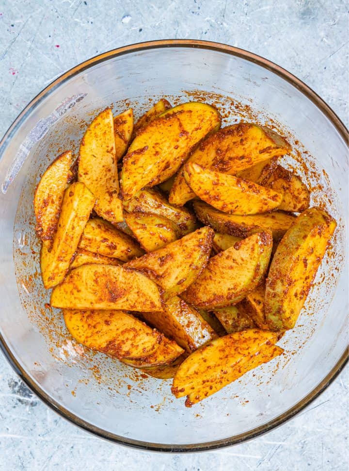 Potato wedges coated in herbs and spices.