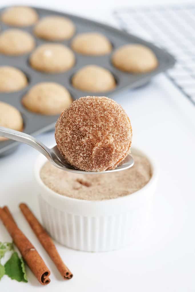 Donut after it has been dipped in cinnamon sugar mixture on spoon.
