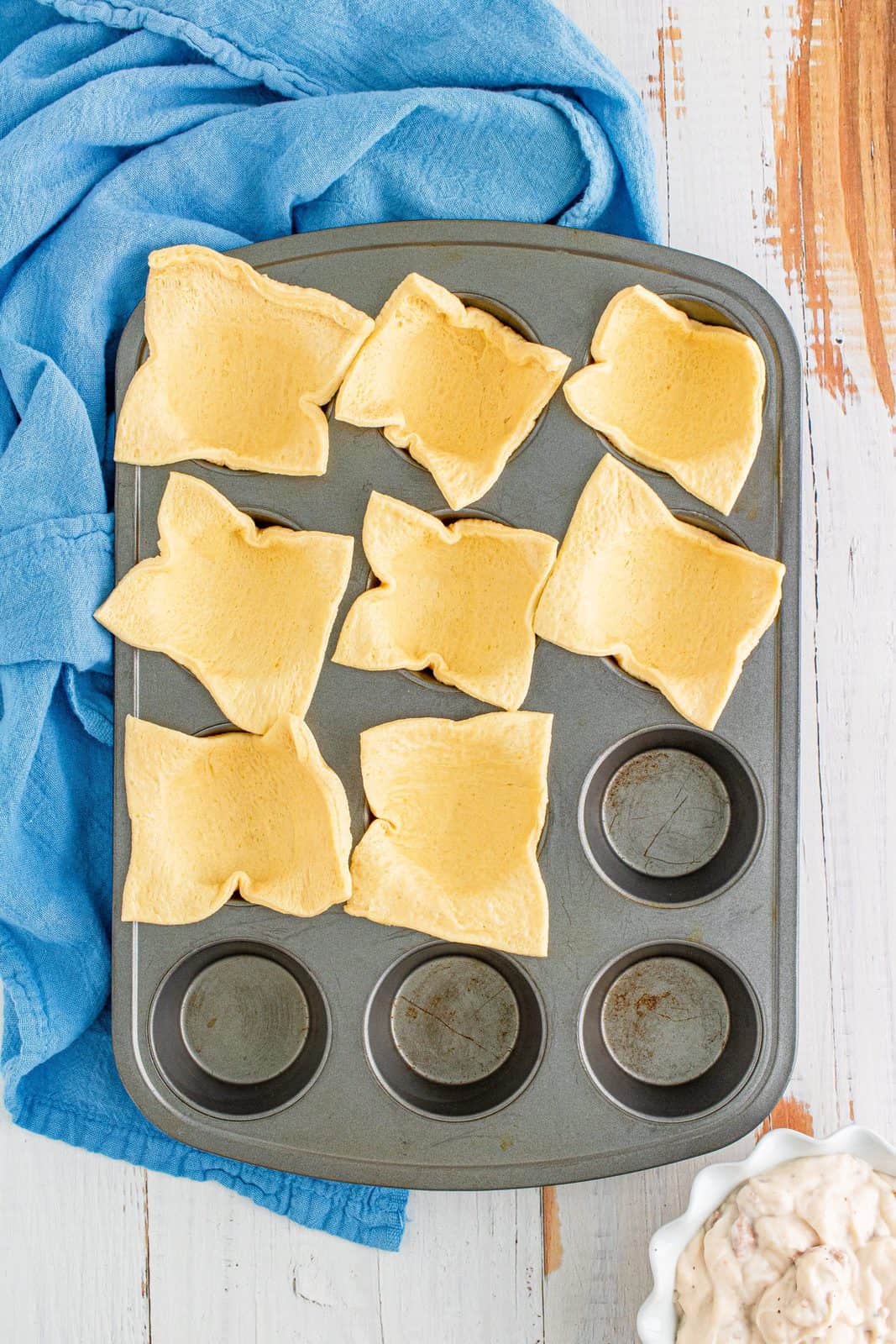 Cut up crescent dough sheet in squares placed in prepared muffin pan.