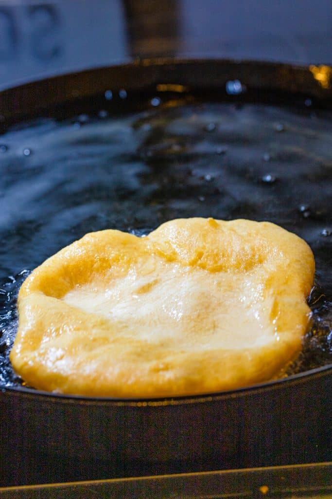 Piece of dough being fried in oil.