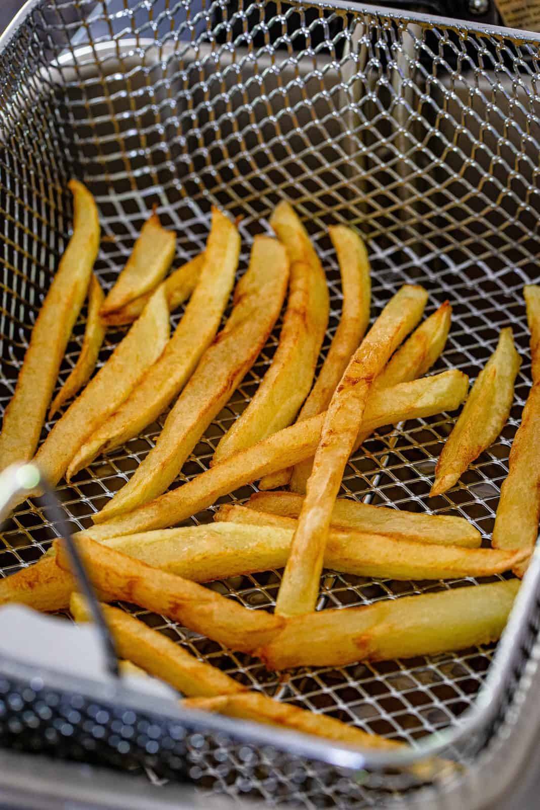 fully fried French fries in a deep fryer basket