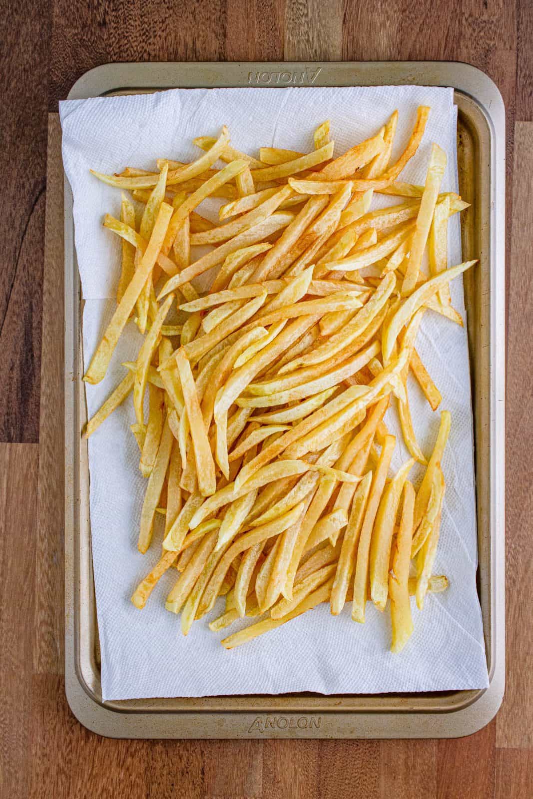 partially cooked French fries on a paper towel to drain excess oil