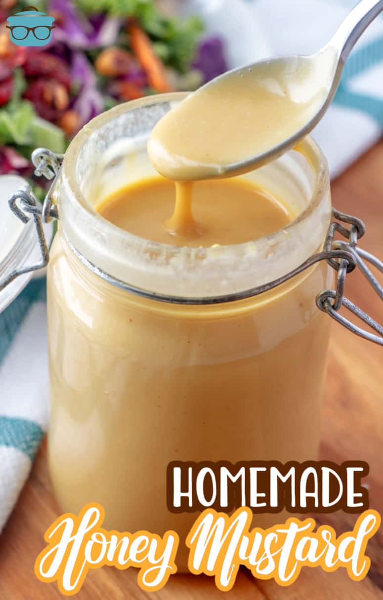 Honey Mustard shown in a mason jar with a spoon pulling out some honey mustard from the jar