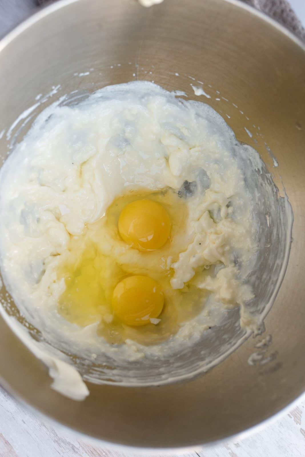 Eggs added to bowl of stand mixer with beaten butter mixture.