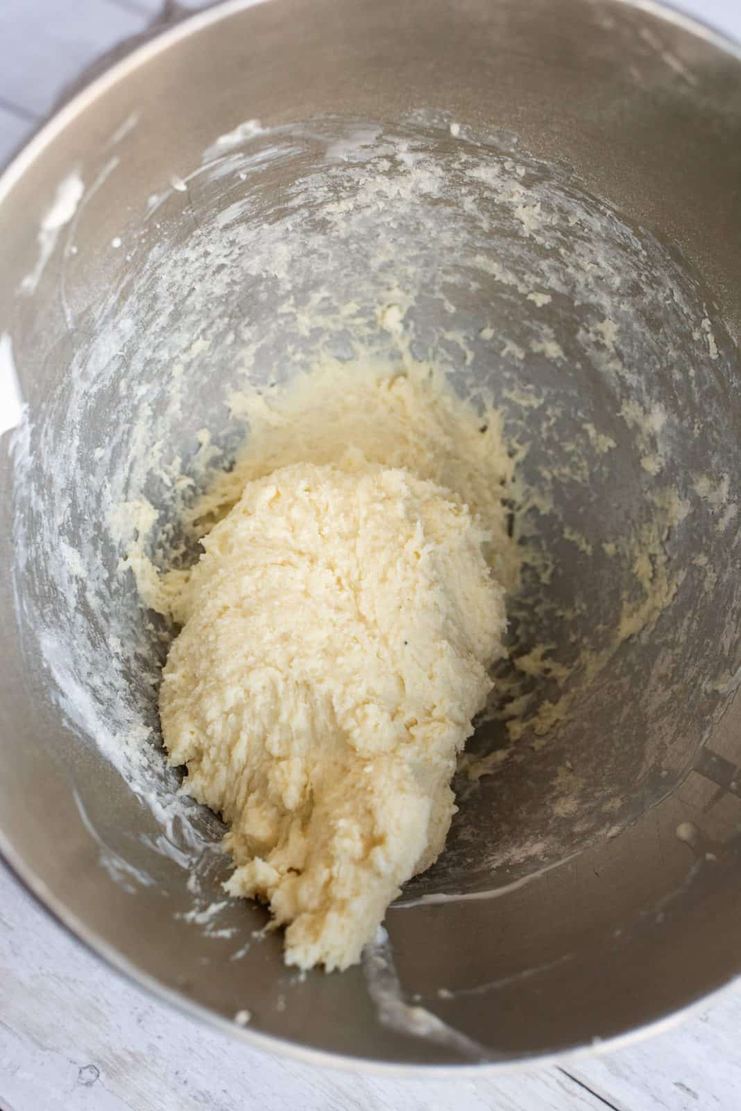 Eggs mixed into butter mixture in bowl of stand mixer.