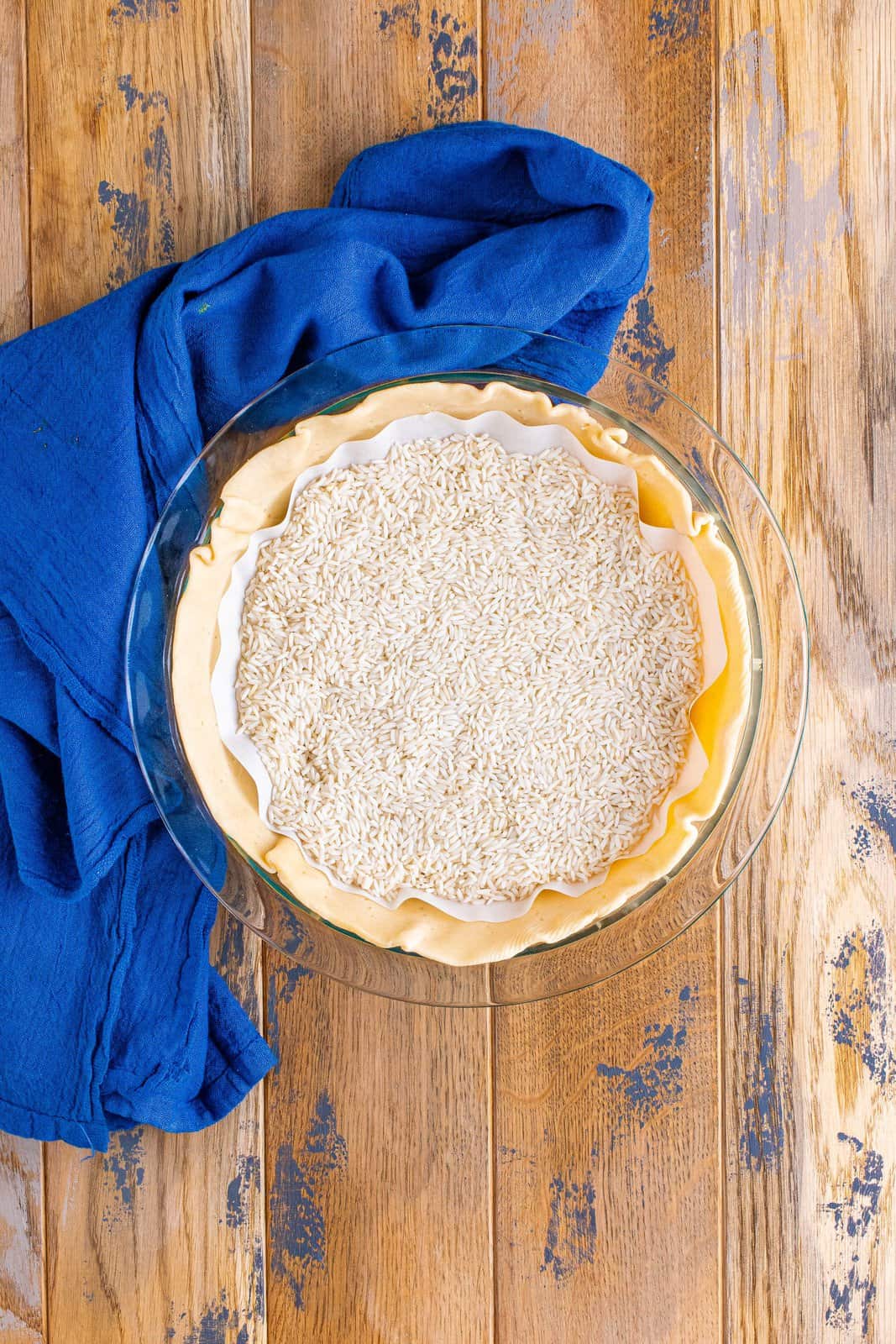 rice added on top of parchment paper on top of pie crust.