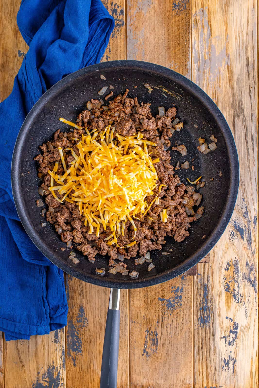 shredded cheese added to beef mixture in skillet. 