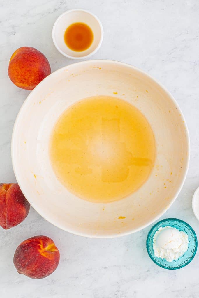 Drained peach juice in large white bowl.