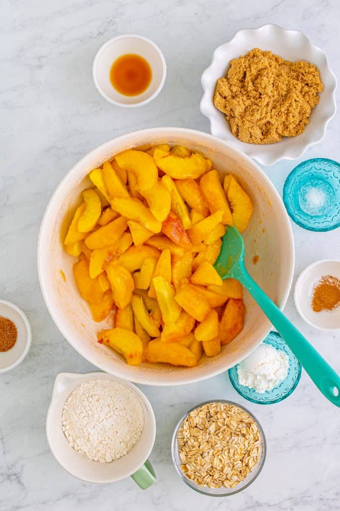Peaches and sugar mixed together in large white bowl.
