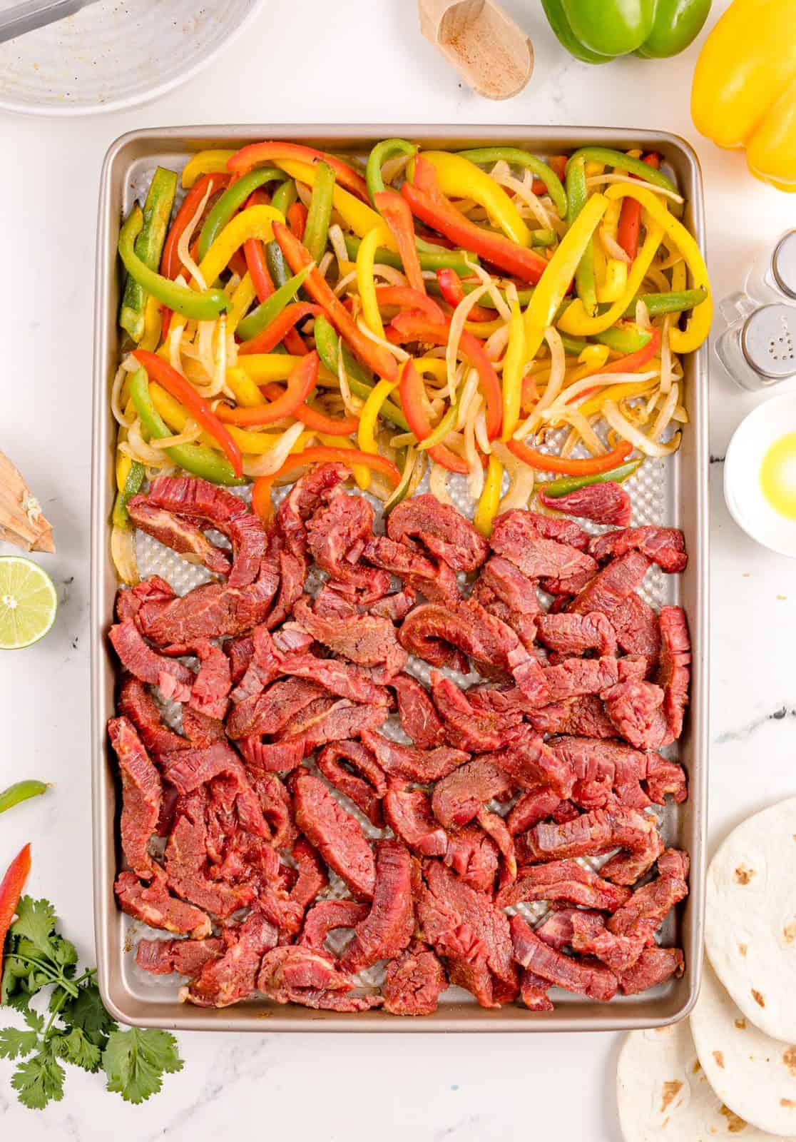Beef added to sheet pan with vegetables.