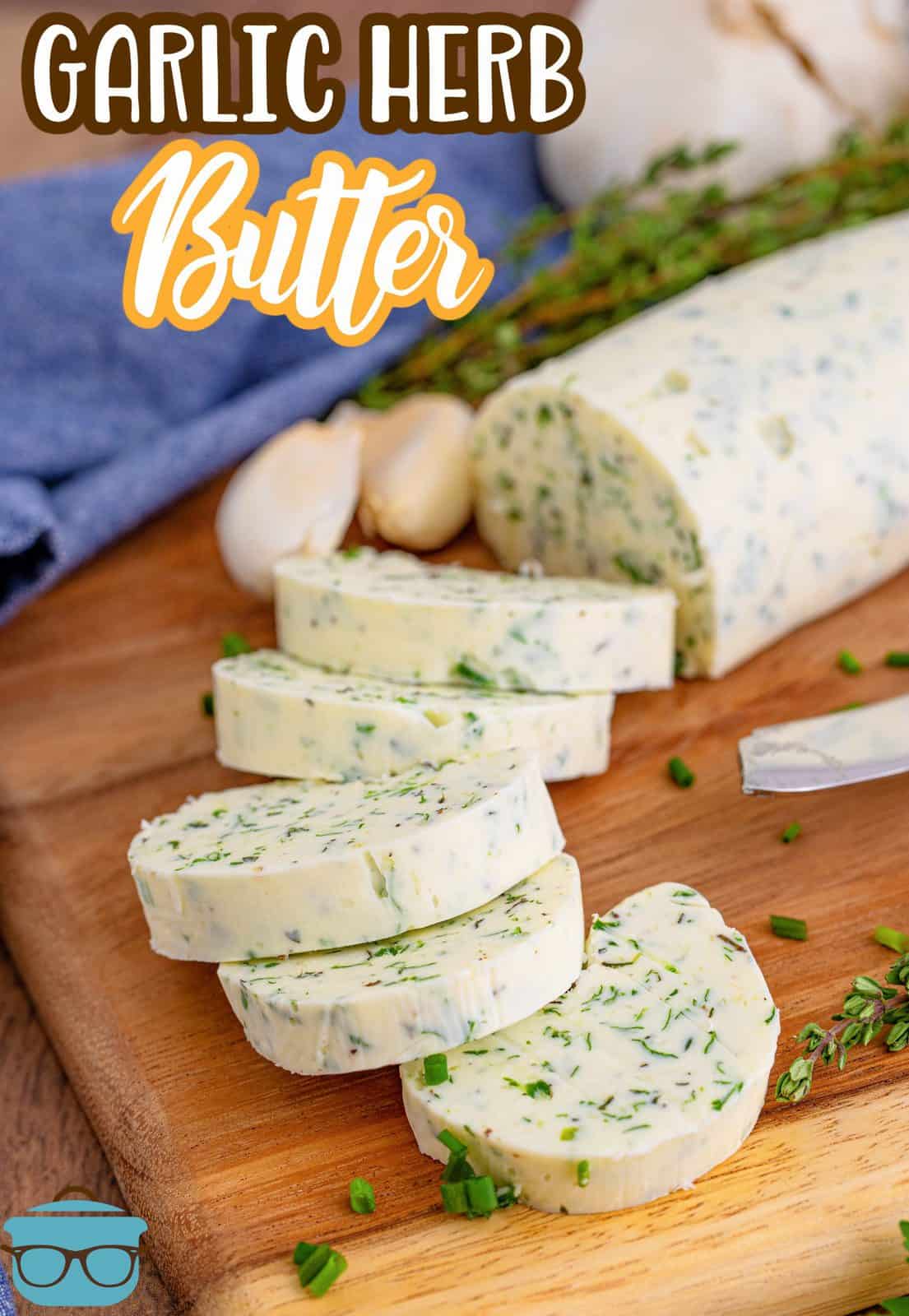 Sliced Garlic Herb Butter in rounds on wooden board with herbs next to butter Pinterest image.