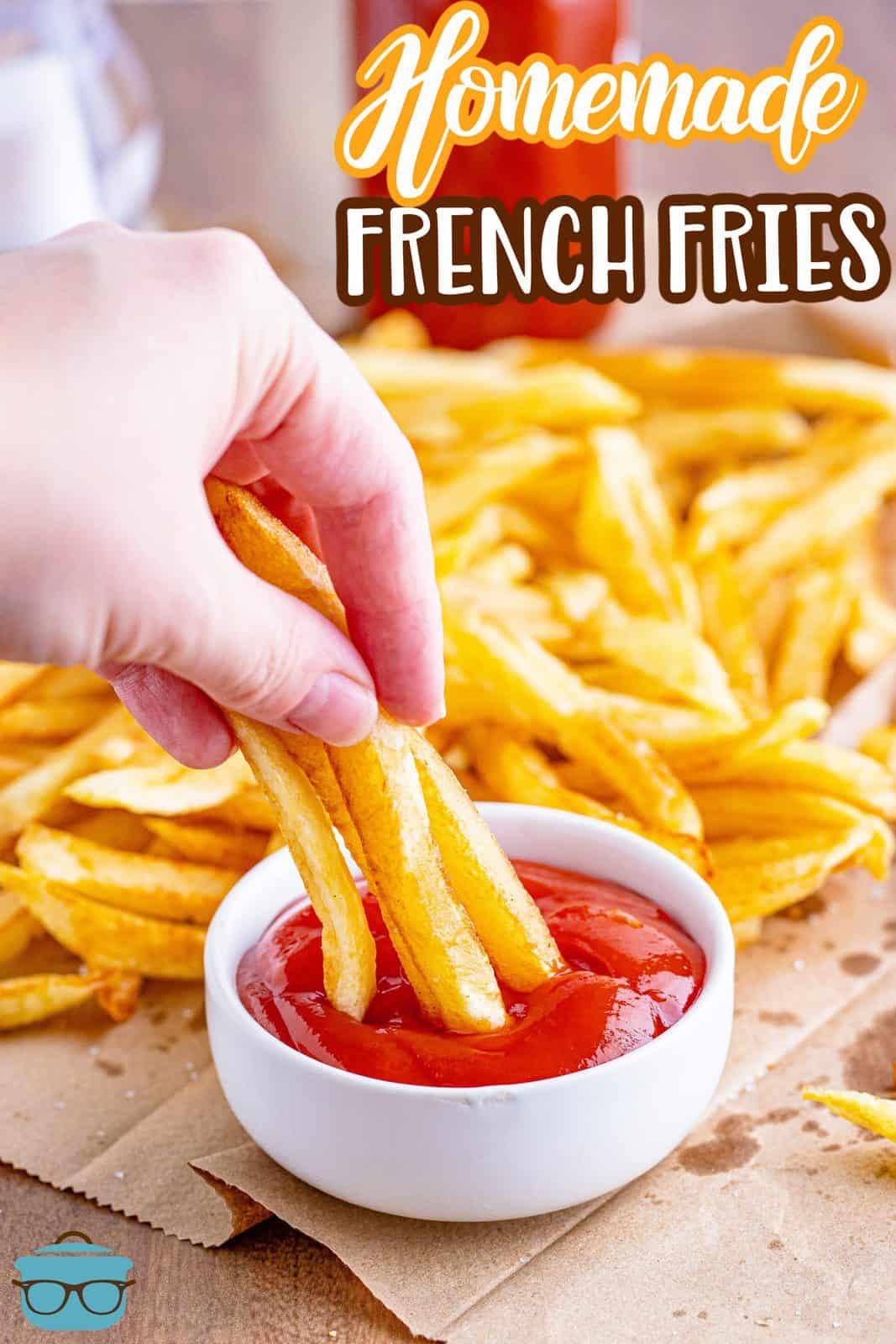 Homemade French Fries recipe from The Country Cook, photo showing a hand dipping a few cooked French Fries into a bowl of ketchup