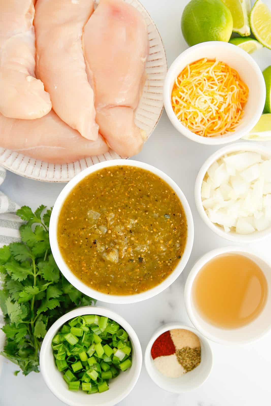 Ingredients needed: chicken breasts, olive oil, onion, green salsa verde, chicken or vegetable broth, chili powder, onion powder, garlic powder, dried oregano, black pepper, kosher salt, mexican cheese, green onions, cilantro and lime wedges.