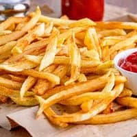 thumbnail photo of fully cooked homemade French Fries on a brown paper towel and ketchup in the background
