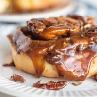 Square image of Homemade Sticky Bun on white plate with pecan sauce.
