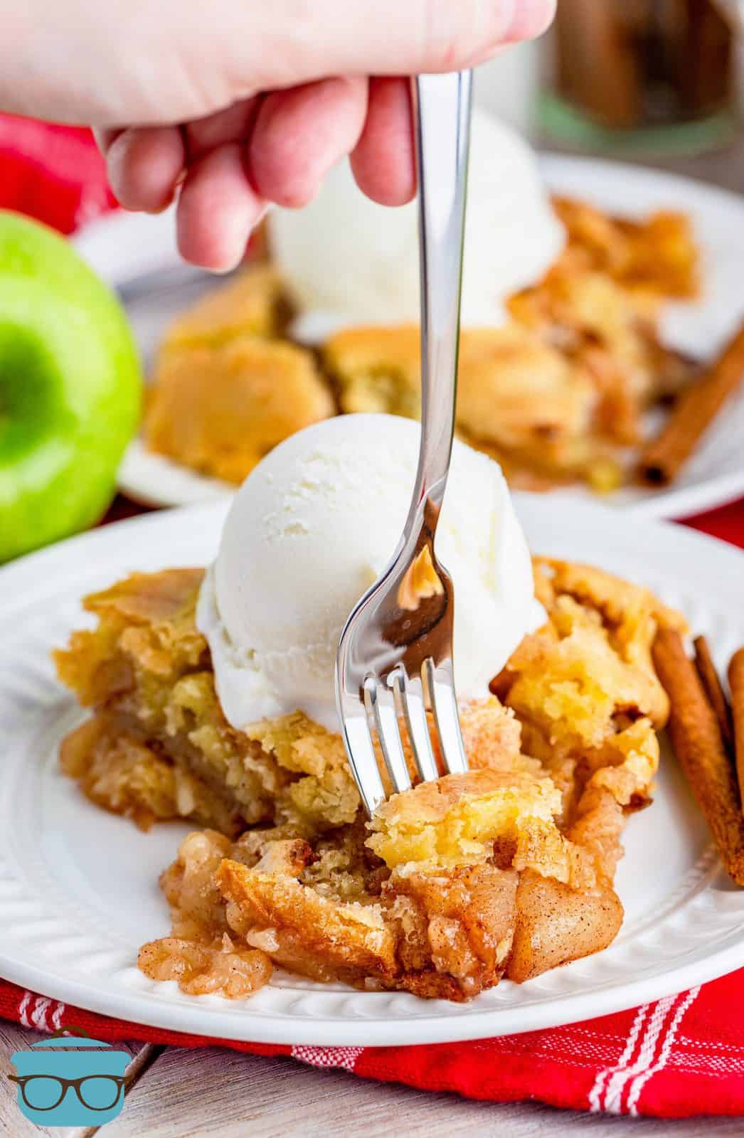 Piece of Grammie's Swedish Apple Pie on plate with ice cream and fork poking into slice.