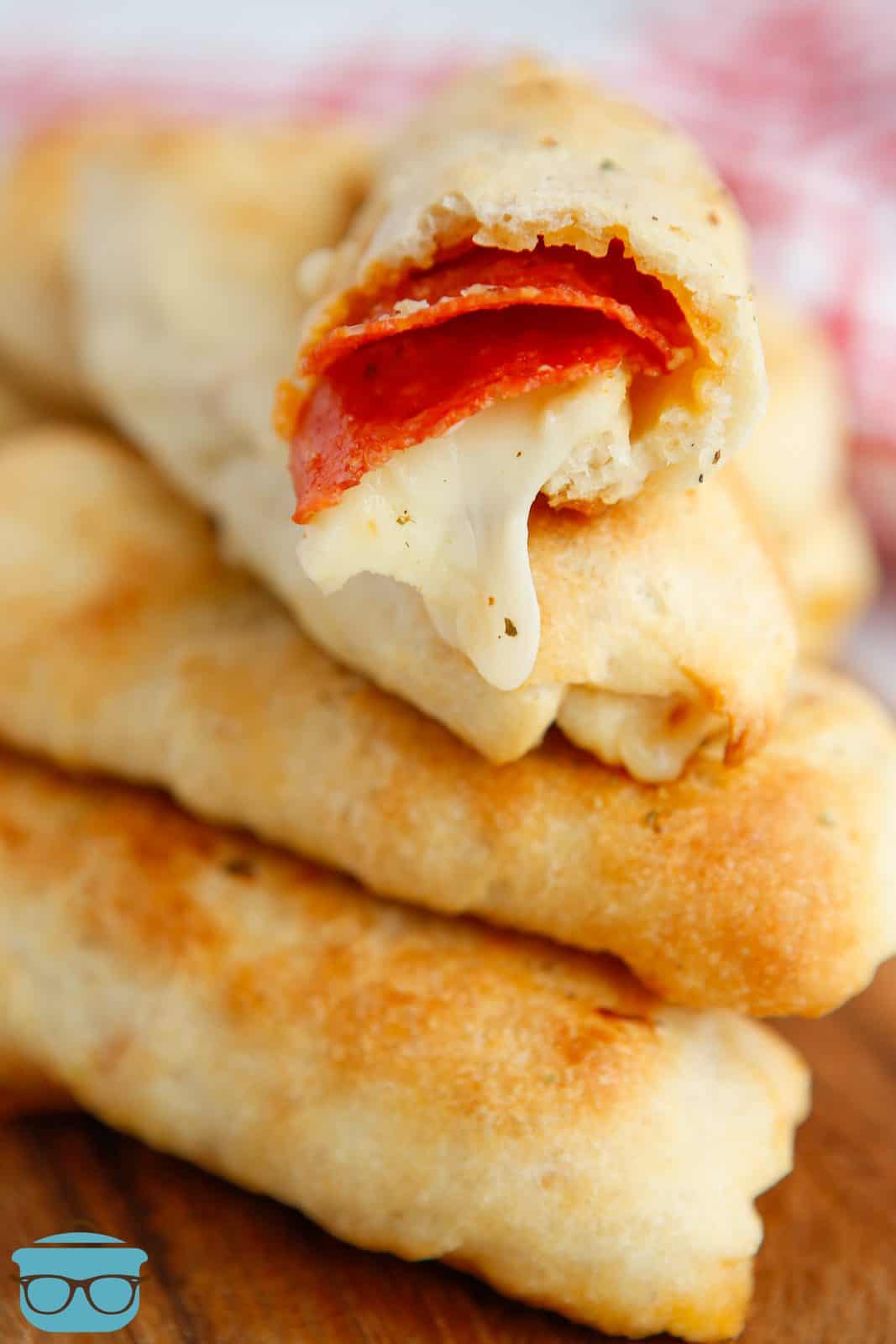 Stacked Pepperoni Pizza Breadsticks with bite taken out of top one showing inside.