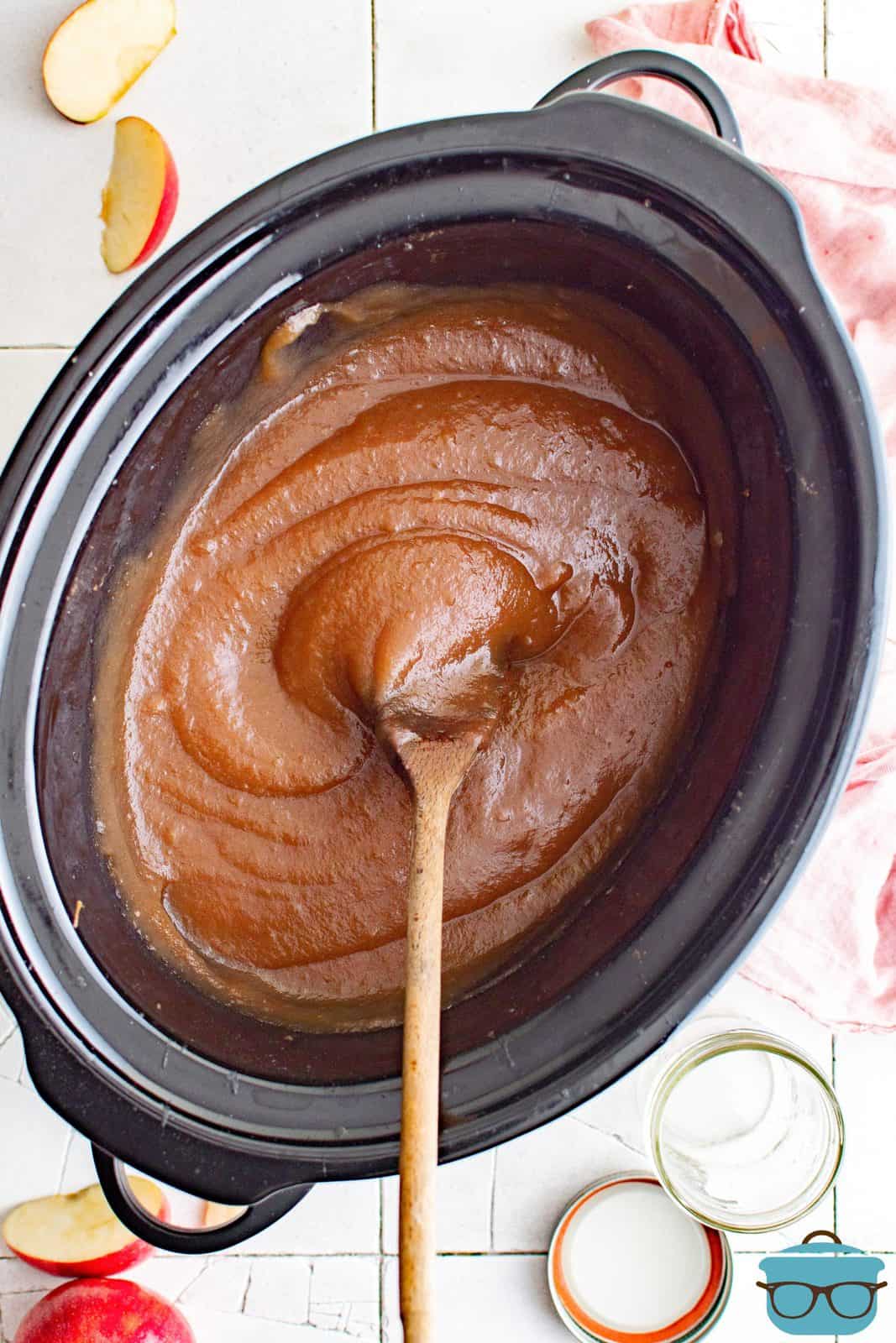 Overhead of smoothe Slow Cooker Apple Butter in slow cooker with wooden spoon.