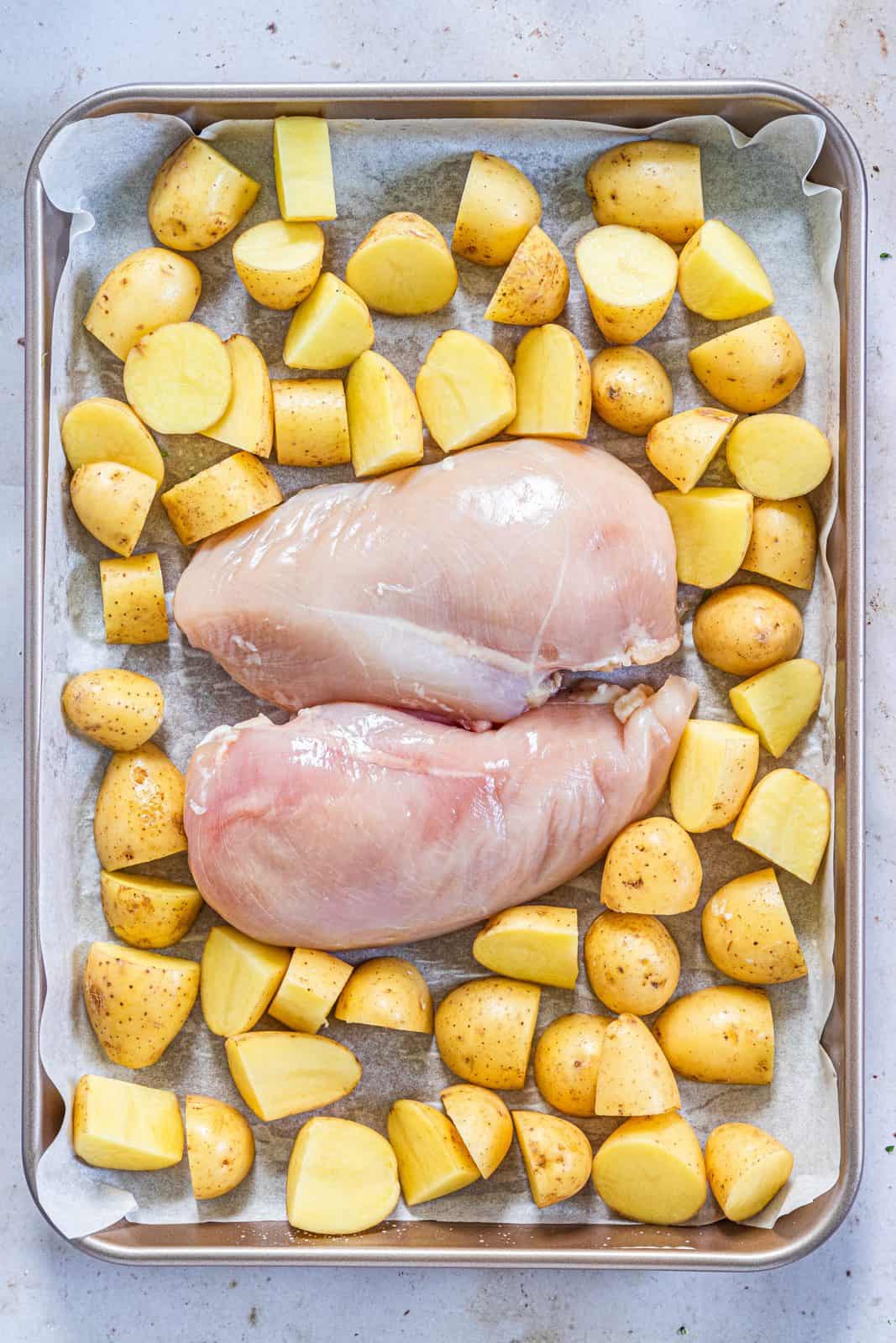 Chicken breasts and potatoes on sheet pan.