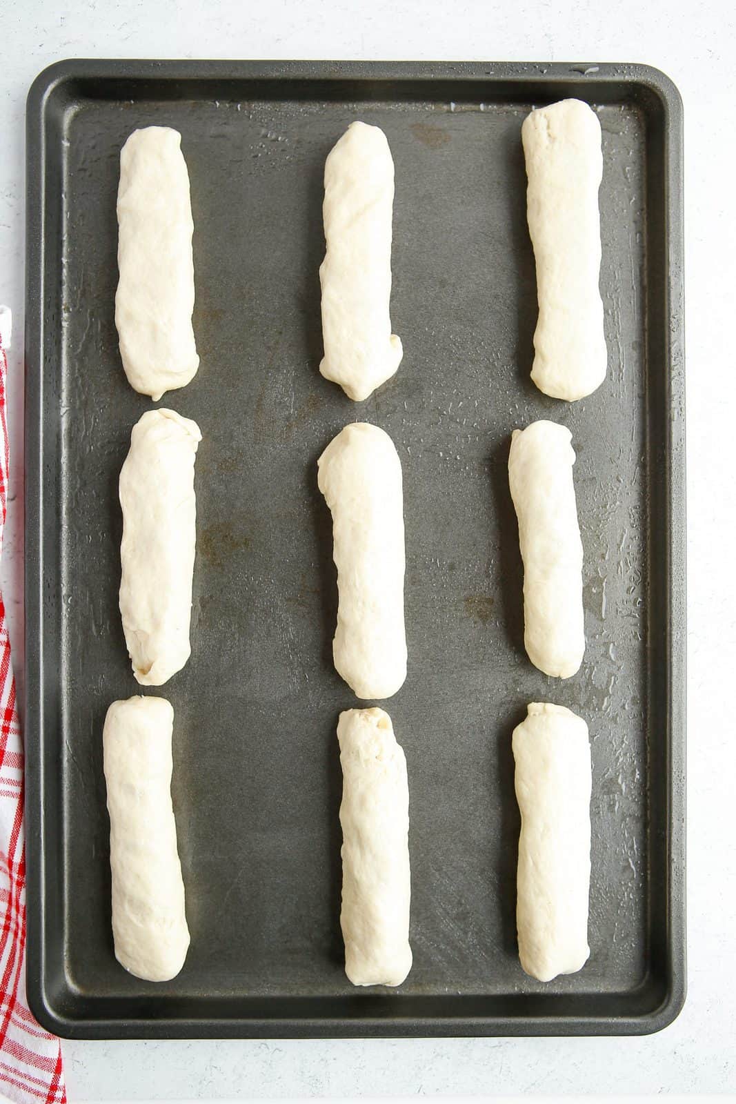 Rolled up and sealed breadsticks on baking sheet.