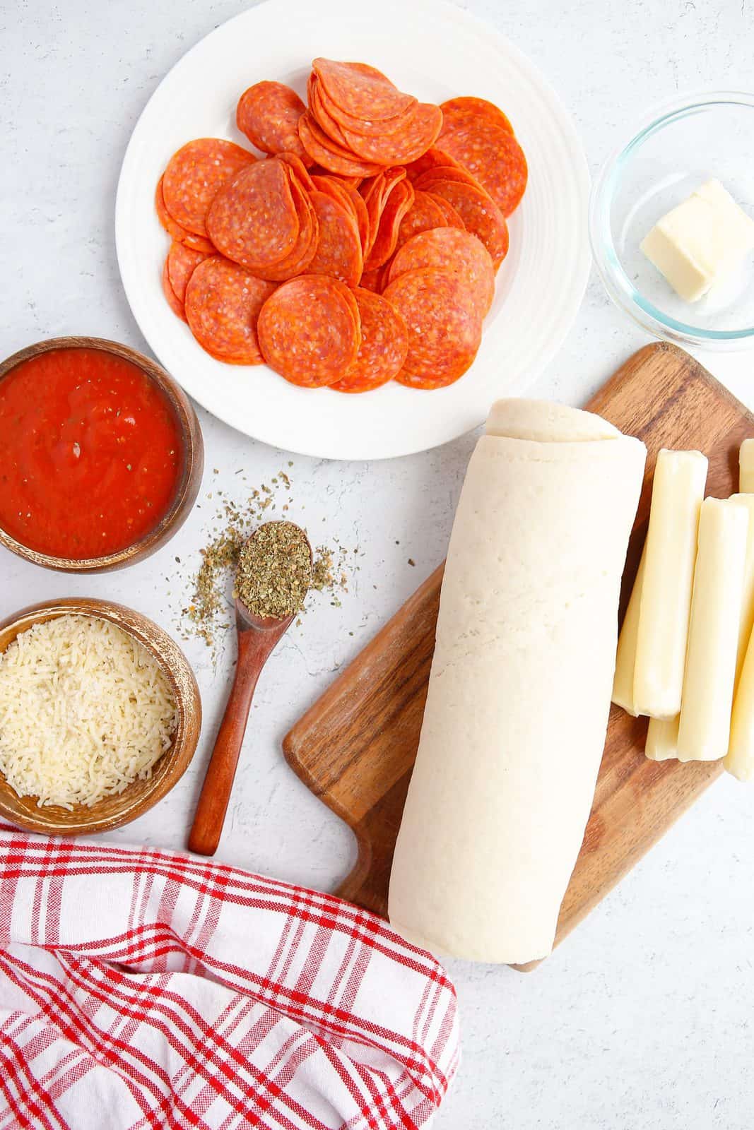 Ingredients needed: prepared pizza dough, pepperoni slices, mozzarella cheese sticks, unsalted butter, dried italian seasoning, parmesan cheese, parsley, marinara sauce and cooking spray.