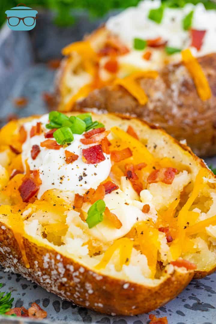 Finished Outback Steakhouse Baked Potatoes topped with cheese, sour cream, bacon and green onions.