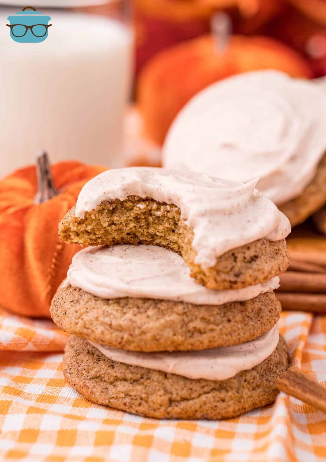 Three stacked Frosted Pumpkin Cookies with bite taken out of the top one.