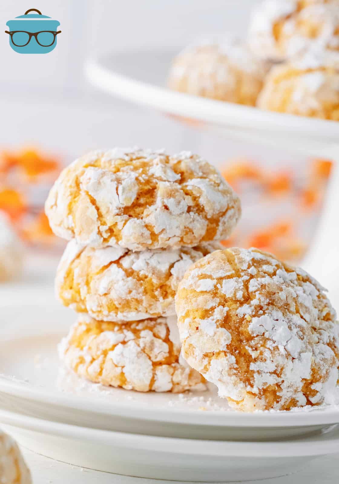 Three stacked Pumpkin Crinkle Cookies on white plate with another cookie leaning against others.