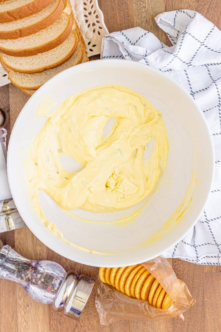 Relish, mayonnaise and mustard whisked together in large white bowl.