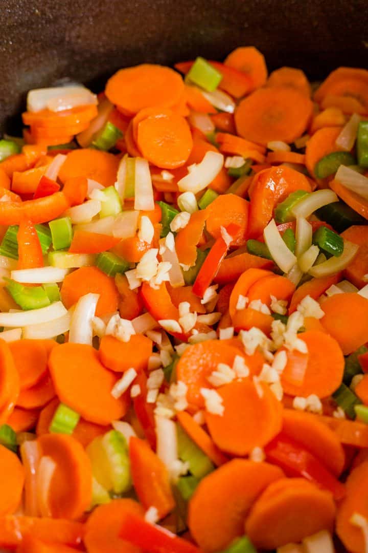 Onion, carrots, celery, pepper and garlic being sauteed in butter in pot.