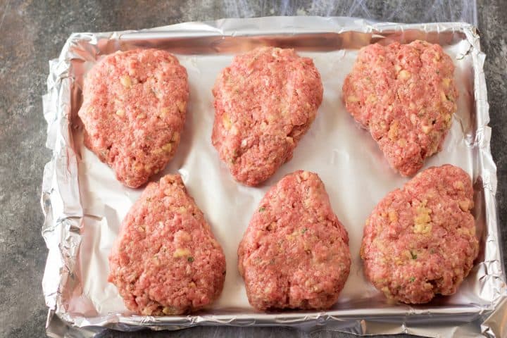 Shaped meatloaf patties on foil lined baking pan.