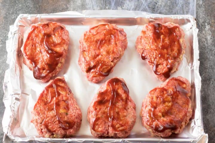 BBQ sauce spread over meatloaf patties.