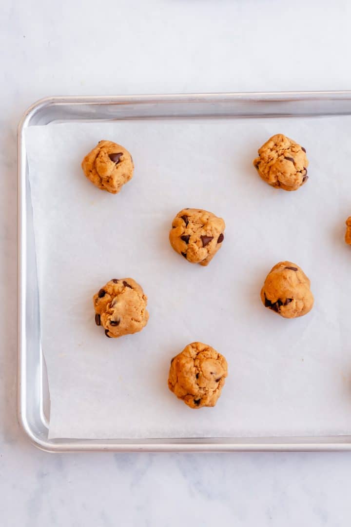 Cookie dough scooped onto parchment lined baking sheet.