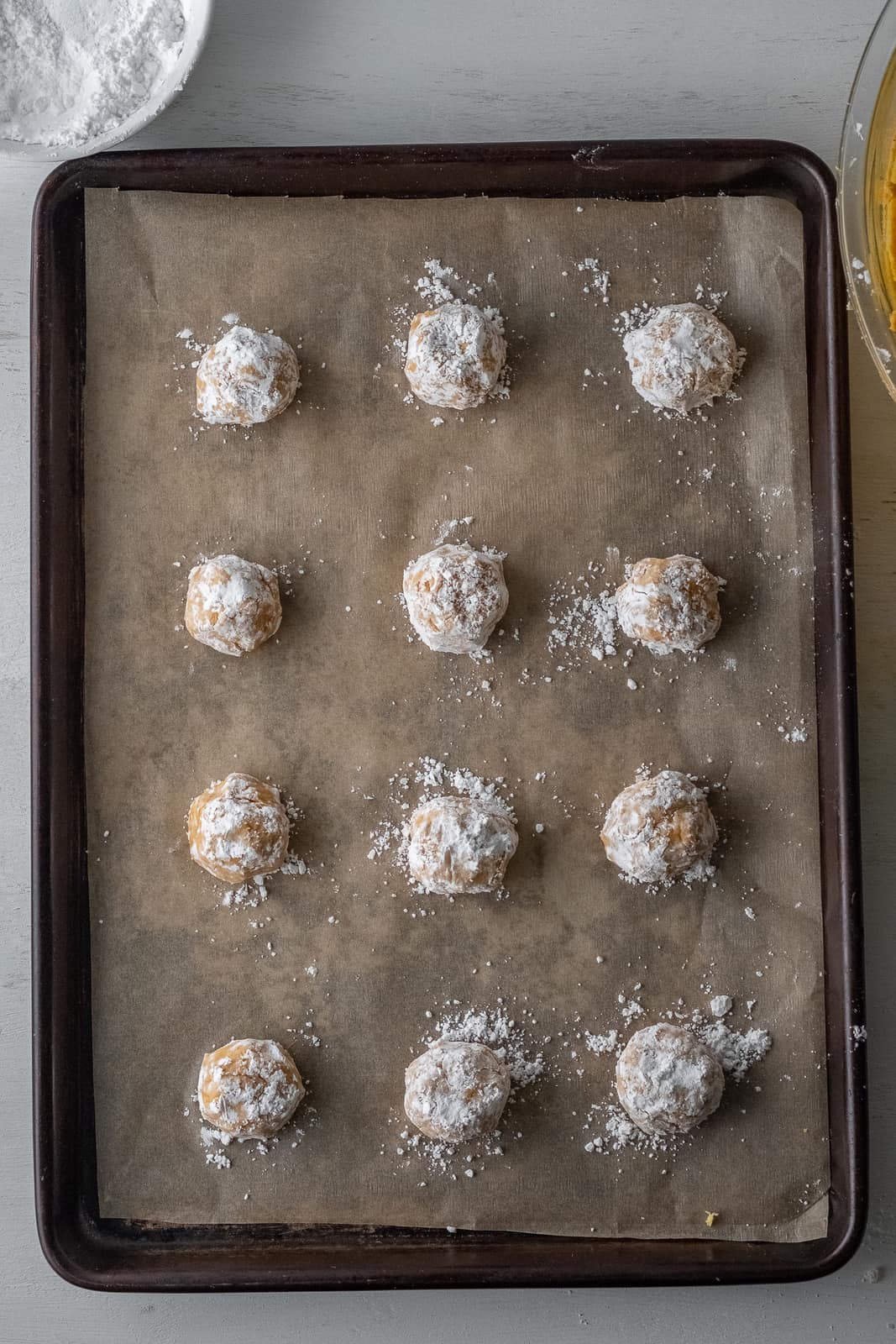 Cookie dough balls added to lined baking sheet.