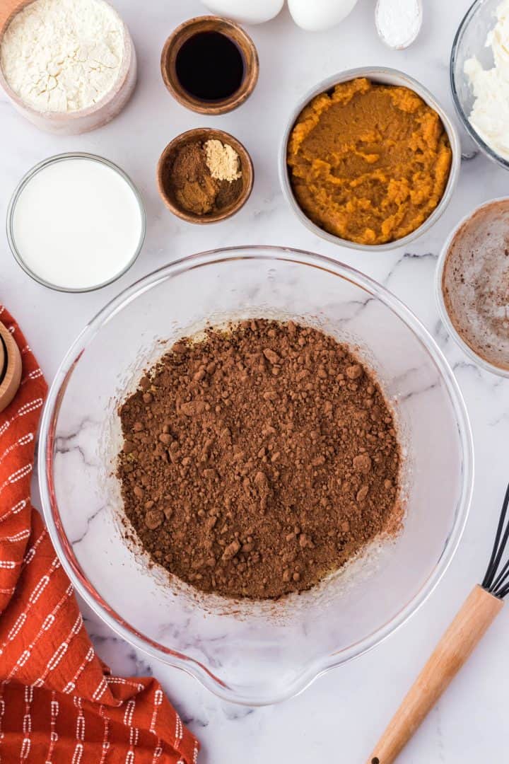 Cocoa powder added to butter mixture in bowl.