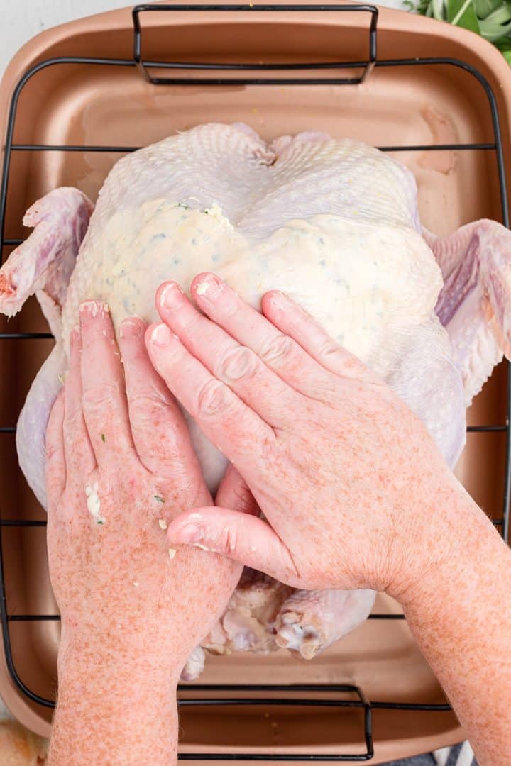 Hands pushing butter around under skin.