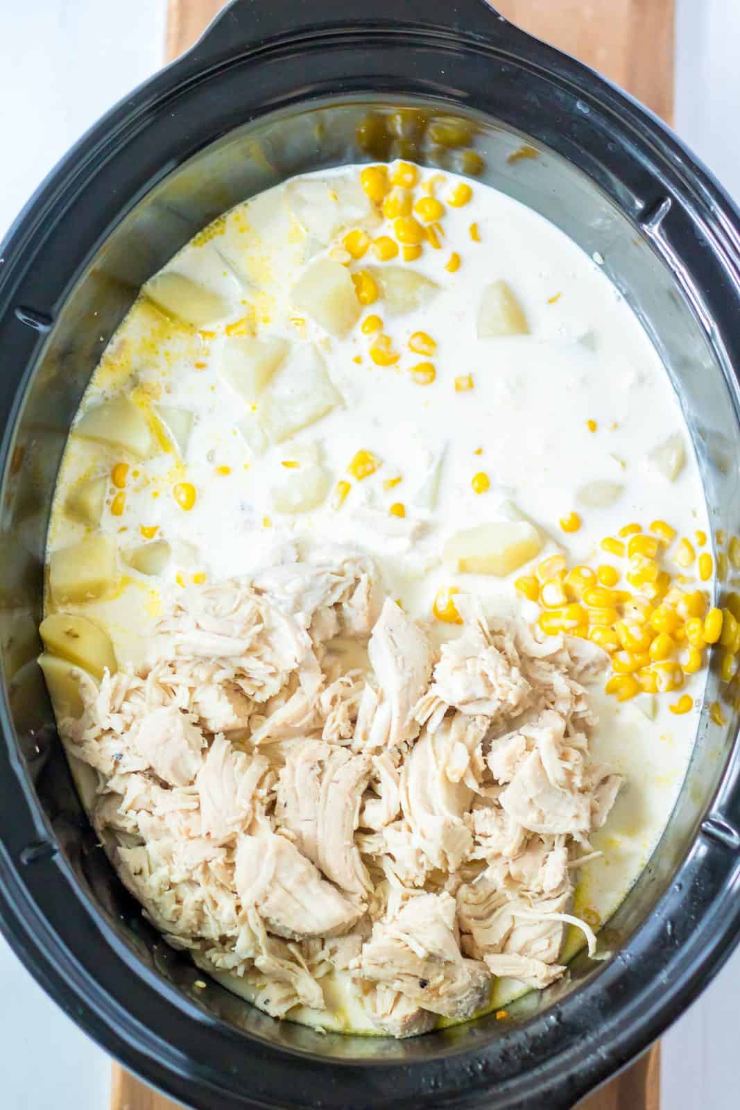 cream, cubed potatoes, onion, chicken broth, chopped turkey and heavy cream shown in a black oval crock pot. 