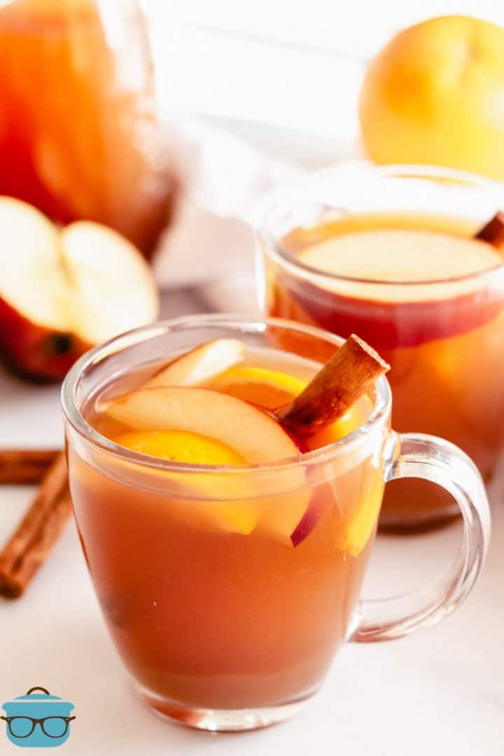 Close up of a mug full of Homemade Apple Cider with apple slices and a cinnamon stick.