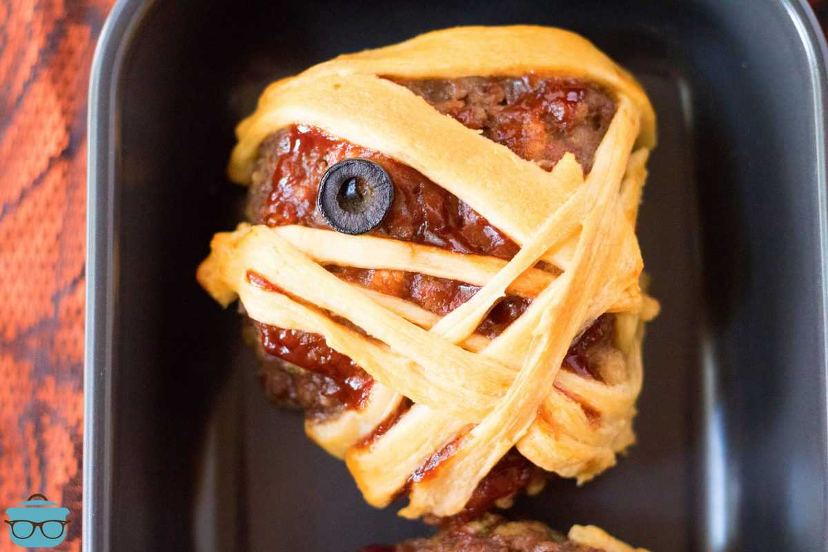 Up close of one Halloween Mummy Meatloaf on black platter showing eye.