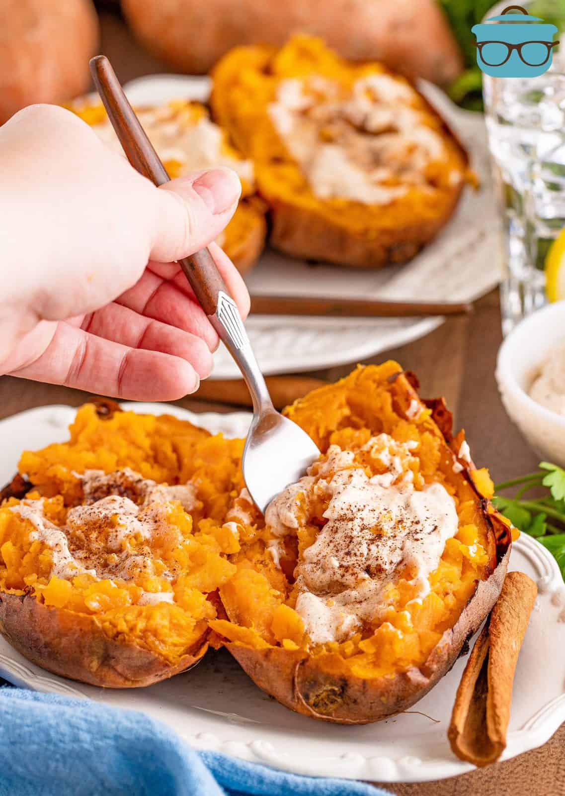 Steakhouse Sweet Potatoes on white platter with cinnamon butter and fork going into potato.