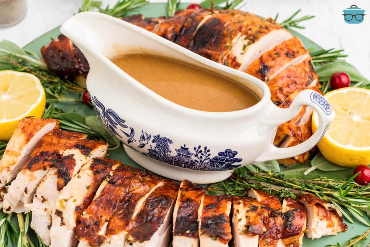 The Best Turkey Gravy Recipe in gravy boat on platter with turkey.