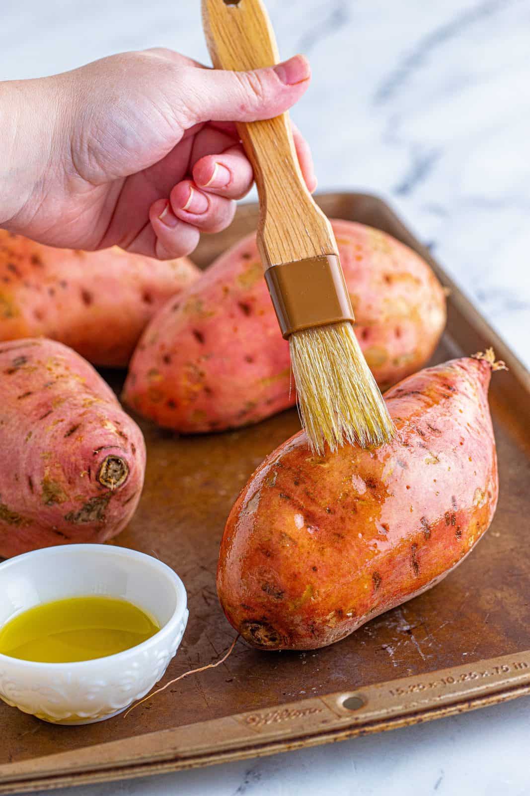 Sweet potatoes being brushed with olive oil.