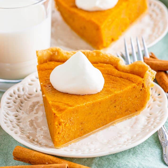 Square image of one slice of Sweet Potato Pie on plate with whipped cream.