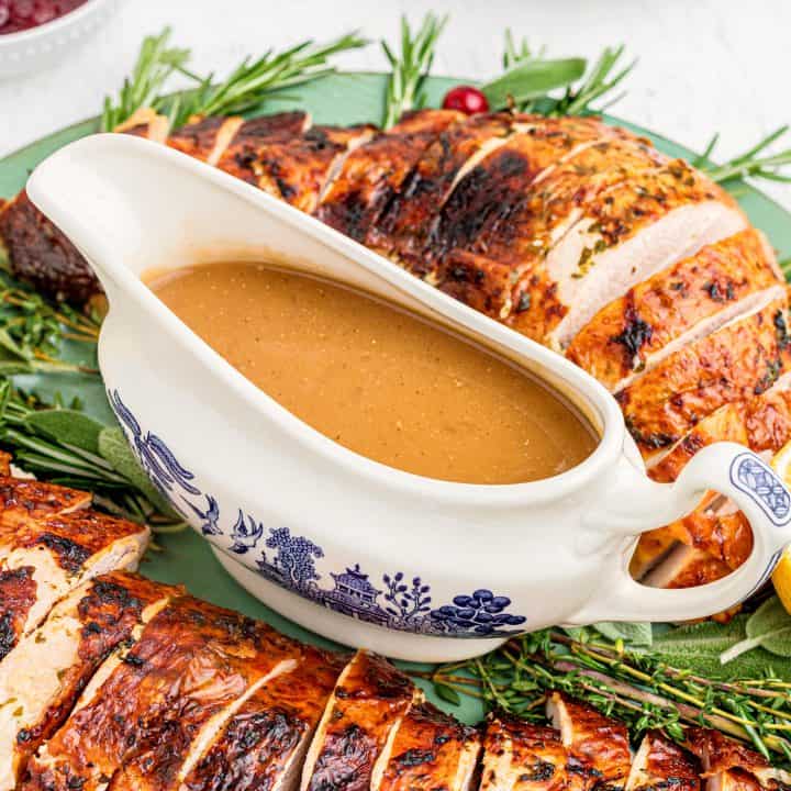 Square image of Turkey Gravy on platter in gravy boat with turkey.