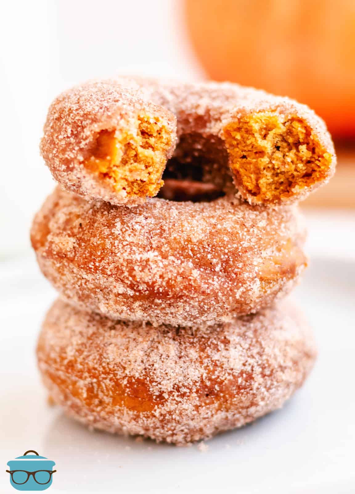 Three stacked Baked Pumpkin Donuts with top donut broken in half.